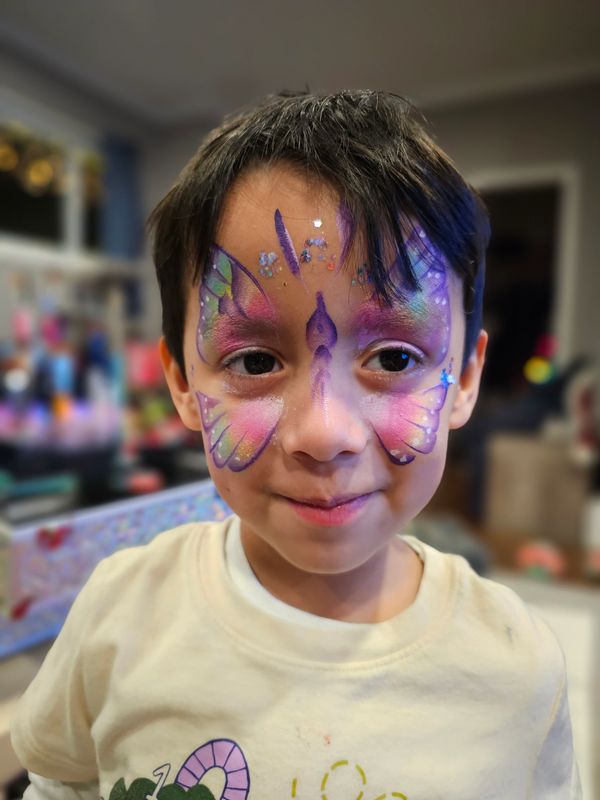 Little boy with a rainbow butterfly painted on his face