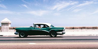a bottle green vintage car on its way in the sunshine and a clear blue sky Arcadia Search recruiter 