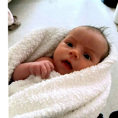 Newborn baby wrapped in a soft white blanket.