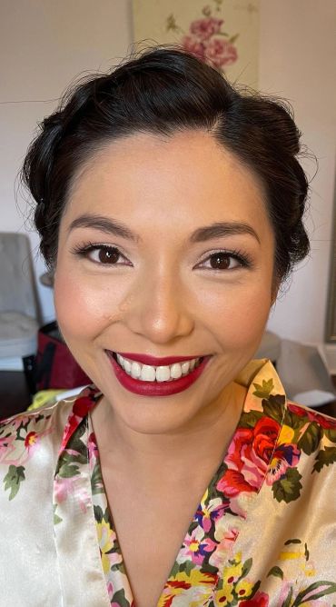 Smiling woman wearing floral robe with bright lipstick.