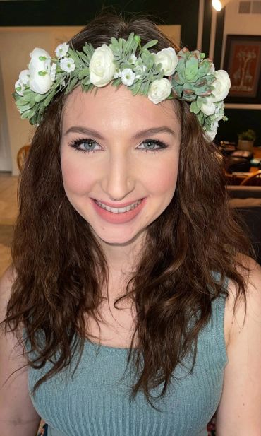 Smiling woman wearing a flower crown with white flowers and succulents.