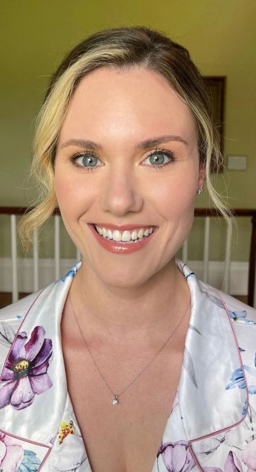 Smiling woman with blonde hair and green eyes.