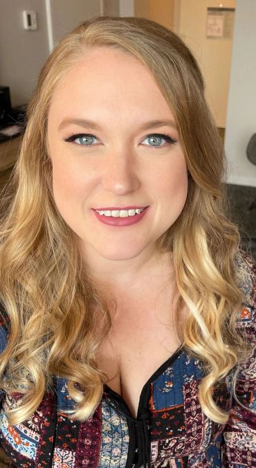 Smiling woman with curled blonde hair and blue eyes.