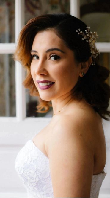Smiling woman in white dress with hair accessory.