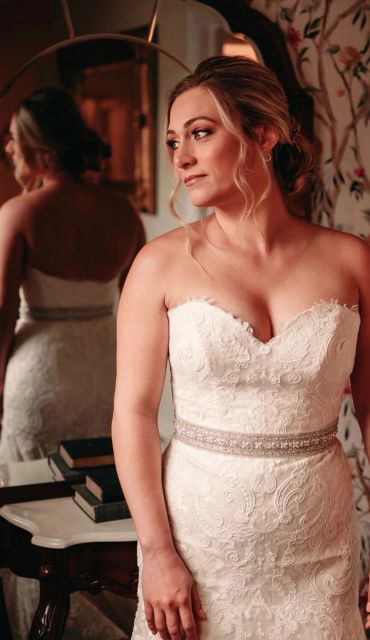 A woman in a lace wedding dress looking to the side.
