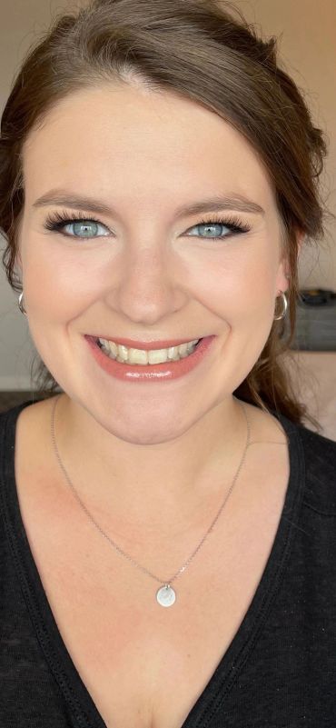 Smiling woman with blue eyes and silver necklace.