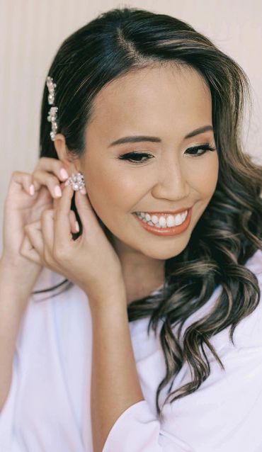 Smiling woman putting on earrings.