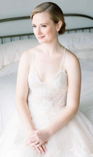 Bride in a white lace wedding dress sitting serenely.