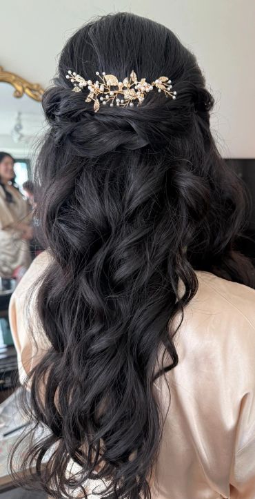 Elegant half-up hairstyle with floral hair accessory.