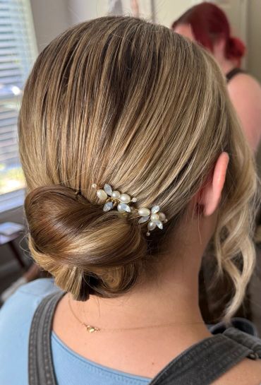 Elegant low bun hairstyle with pearl hairpin.