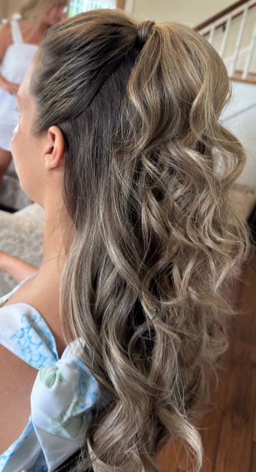 Curly half-up hairstyle with blonde highlights.