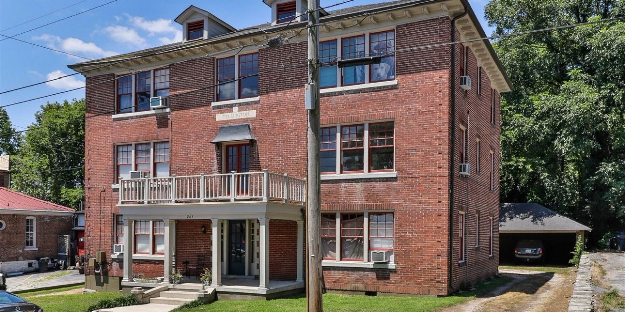 Three-story brick apartment building with balcony.
