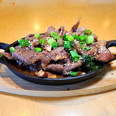 Korean beef bulgogi served sizzling on a cast iron plate