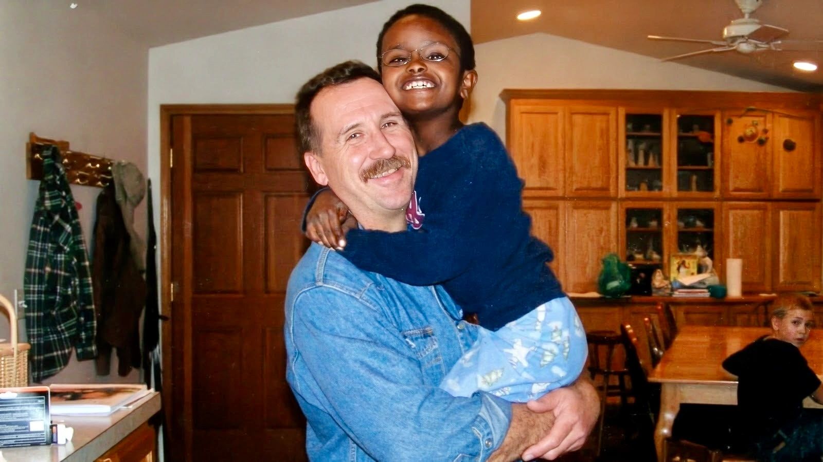 Man holding a smiling child in a cozy kitchen.