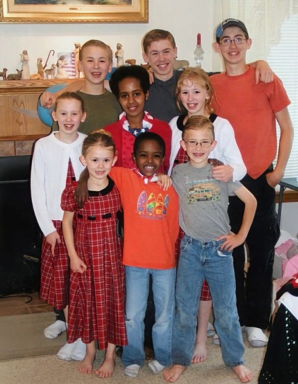 Group photo of nine smiling children indoors.