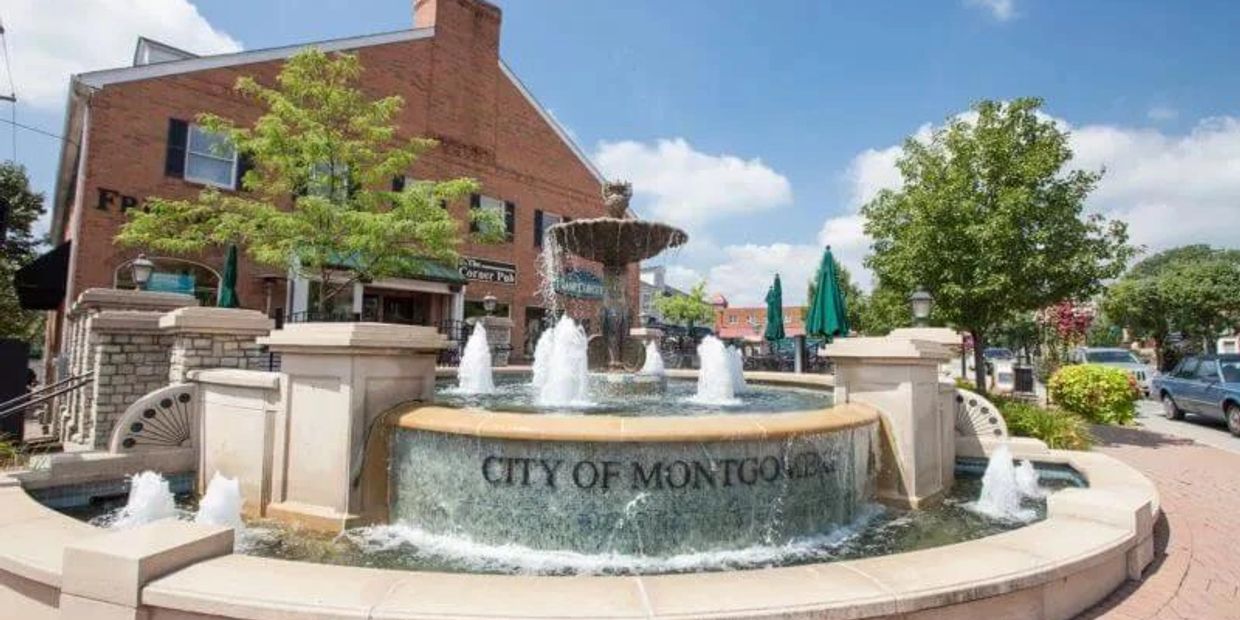 Fountain in downtown Montgomery with clear water jets and brick buildings.