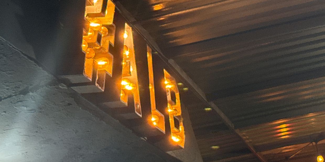 Illuminated sign reading 'HALB' with warm yellow lights.