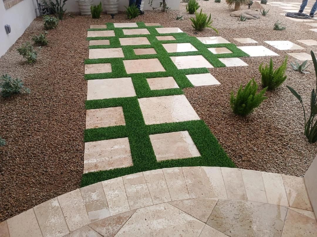 Stepping stones on artificial grass with gravel and plants.