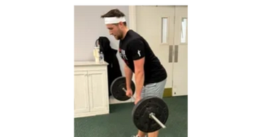 Man lifting a barbell in a gym setting.