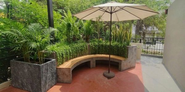 Cozy outdoor curved bench with umbrella surrounded by lush greenery.