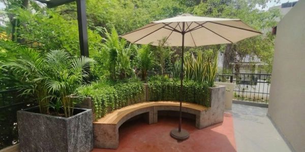 Cozy outdoor curved bench with umbrella surrounded by lush greenery.