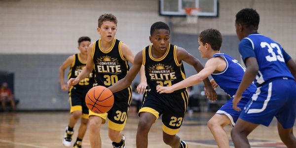 Youth basketball game with players in black and blue jerseys.