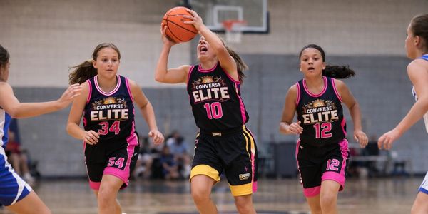Young female basketball players in black Converse Elite uniforms during a game.