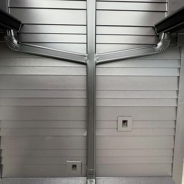 Metallic pipes arranged symmetrically on a gray wall.