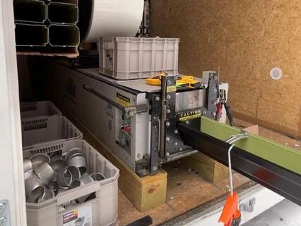 Industrial machine with metal parts and conveyor belt in a workshop.
