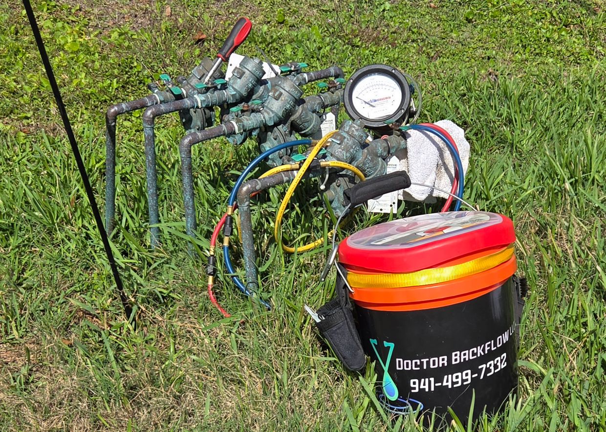 Backflow testing equipment with a tool bucket on grass.