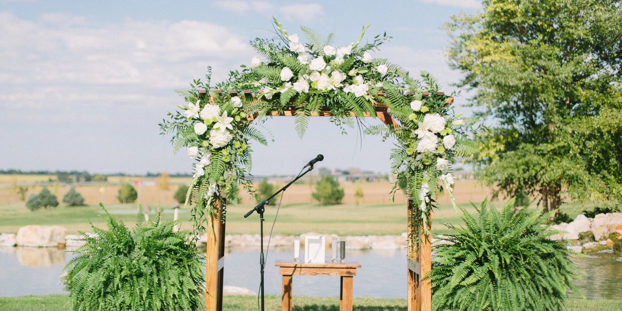 Outside wedding venue arbor decorated in front of the small pond.