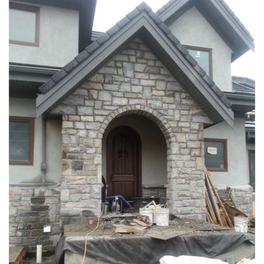 Stone-arched entrance under construction on a modern house.