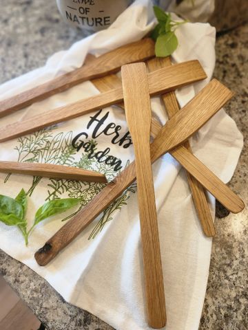 Wooden herb garden markers on a white cloth with greenery.