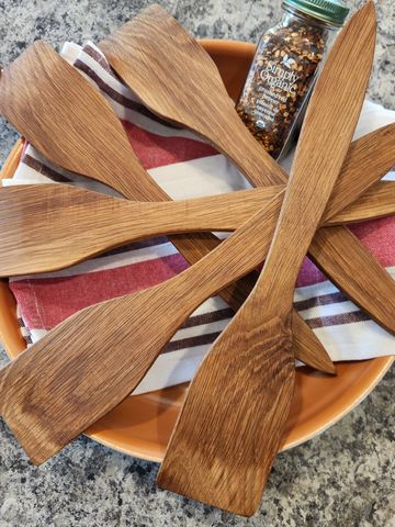 A set of wooden spatulas arranged on a plate with a spice jar in the background.