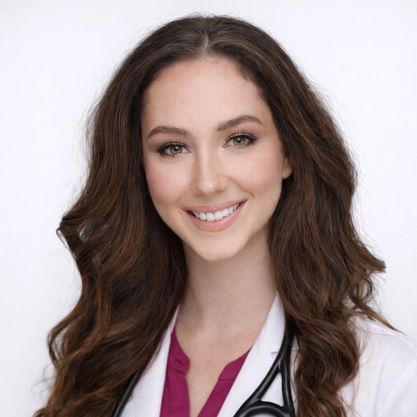 Smiling female doctor with long brown hair and stethoscope.