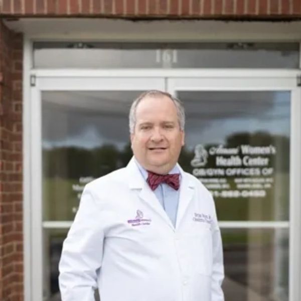 Doctor in white coat standing outside a women's health center.