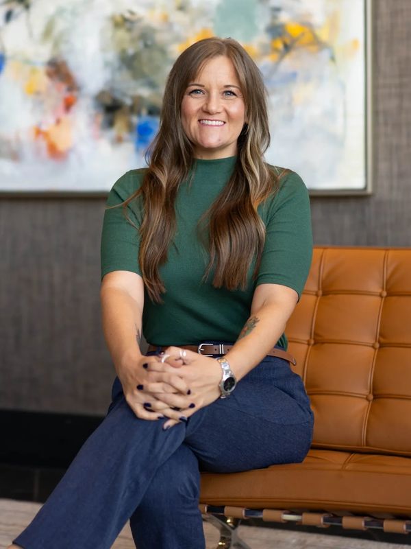 A woman sitting on a modern leather chair, smiling confidently.