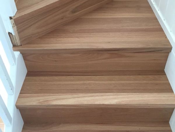 Wooden stairs with a light natural finish and white railing sides.