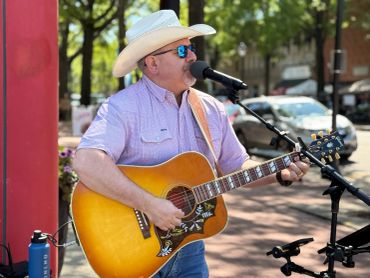 Man in a cowboy hat playing guitar and singing into a microphone.