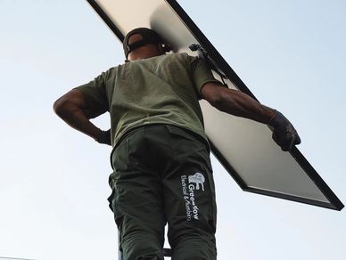 Electrician carries solar panel into roof