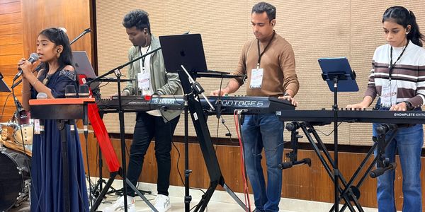 Group of musicians performing with keyboard and singing.