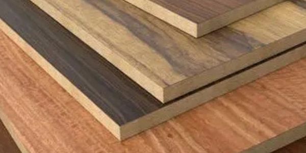 Stacked wooden plywood sheets with varying wood grain patterns and colors.