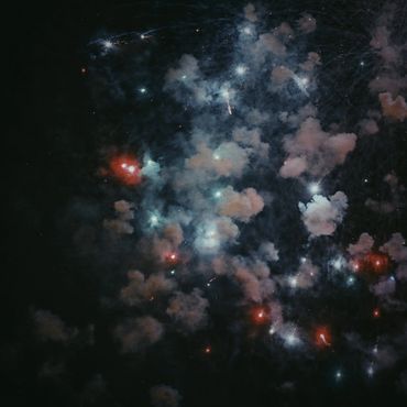 The aftermath of fireworks on Coney Island. Red, white, & blue clouds of smoke in the sky 