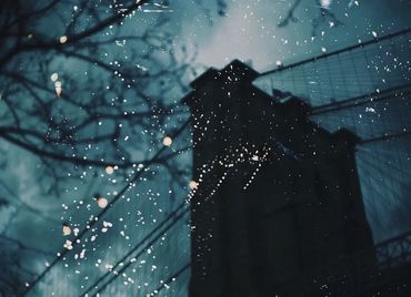 double exposure- blue twilight sky, silhouette of Brooklyn Bridge, white twinkling lights overlayed