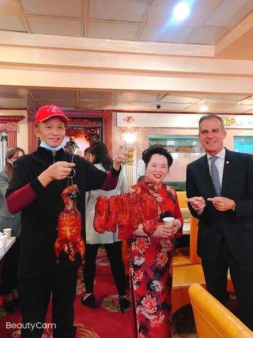 Chef Lupe holding up Chinese BBQ with Judy & Mayor Eric Garcetti
