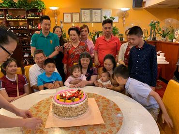 Group of people gathered around a birthday cake.