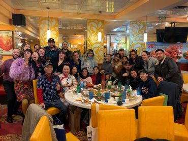 Group of people smiling inside Hop Woo restaurant.