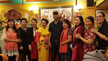 Group of people smiling inside Hop Woo restaurant.