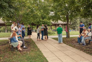 People gathered in a park on a sidewalk.