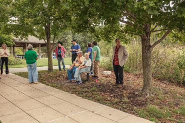 Group of people gathered in a park under trees.